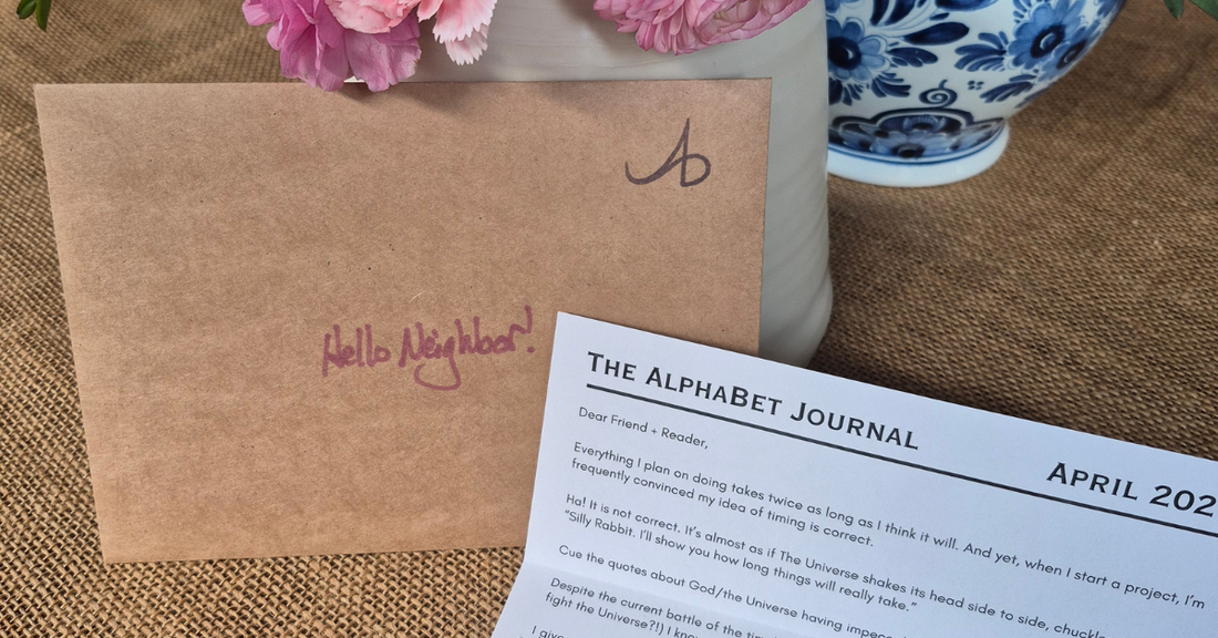 Upright envelope resting against a flower arrangement with an open typed letter in front of it