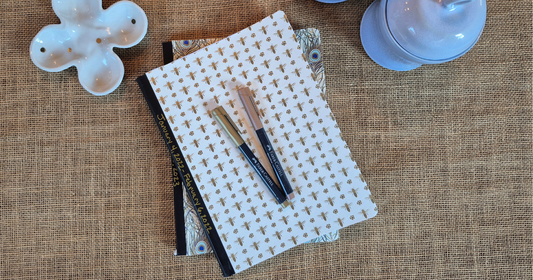Closed journal on a jute background with colorful markers and pretty pottery, representing a daily writing ritual