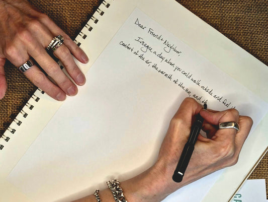Hands writing a handwritten letter in a spiral notebook — why I write to strangers 
